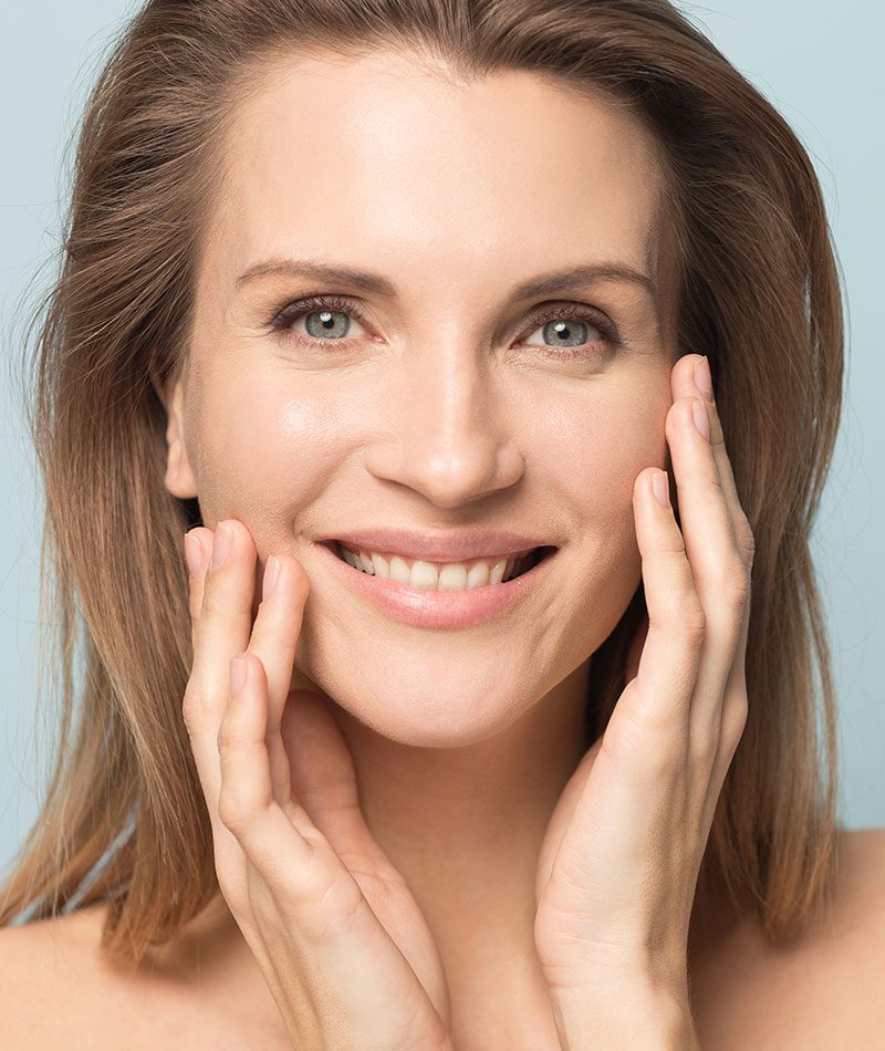 Smiling woman gently hold her hands to her cheeks