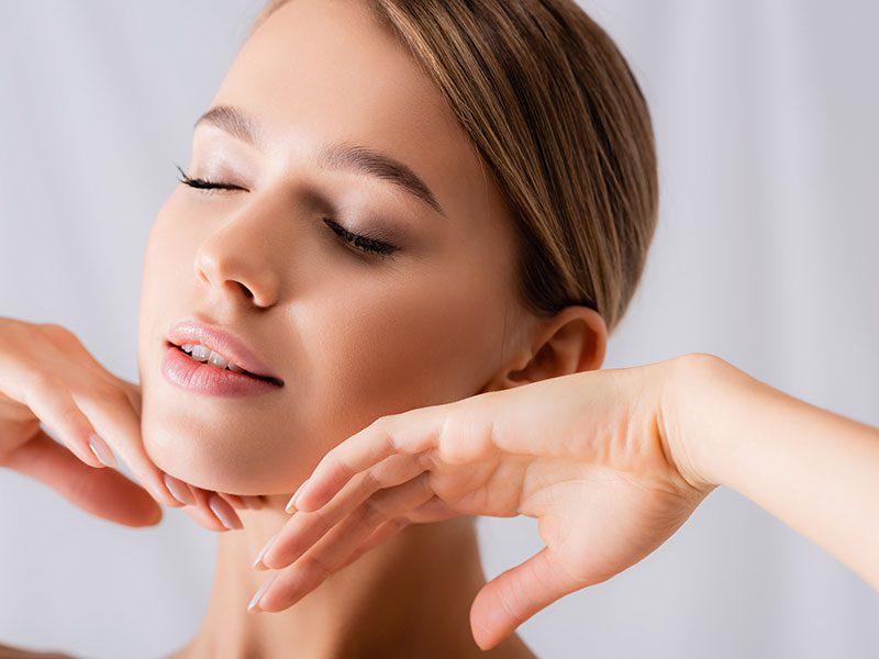 Young adult woman brushing her hands along her chin