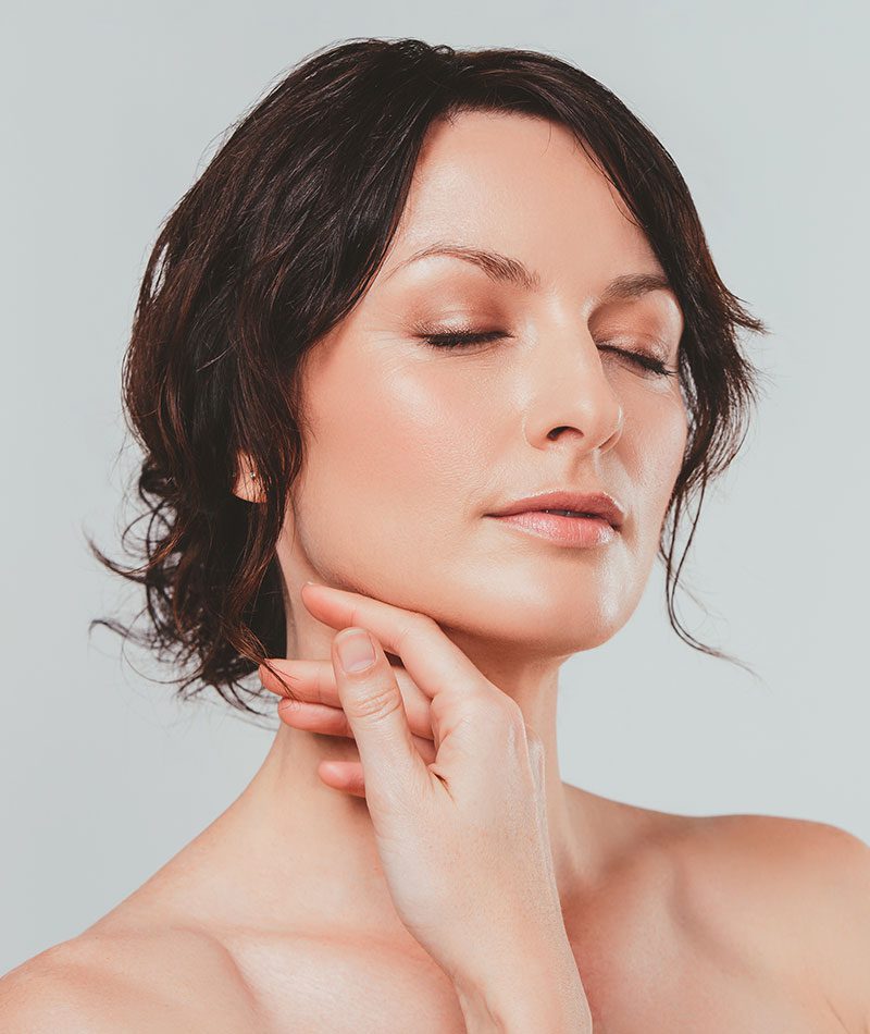Woman with bare shoulders caressing her jaw