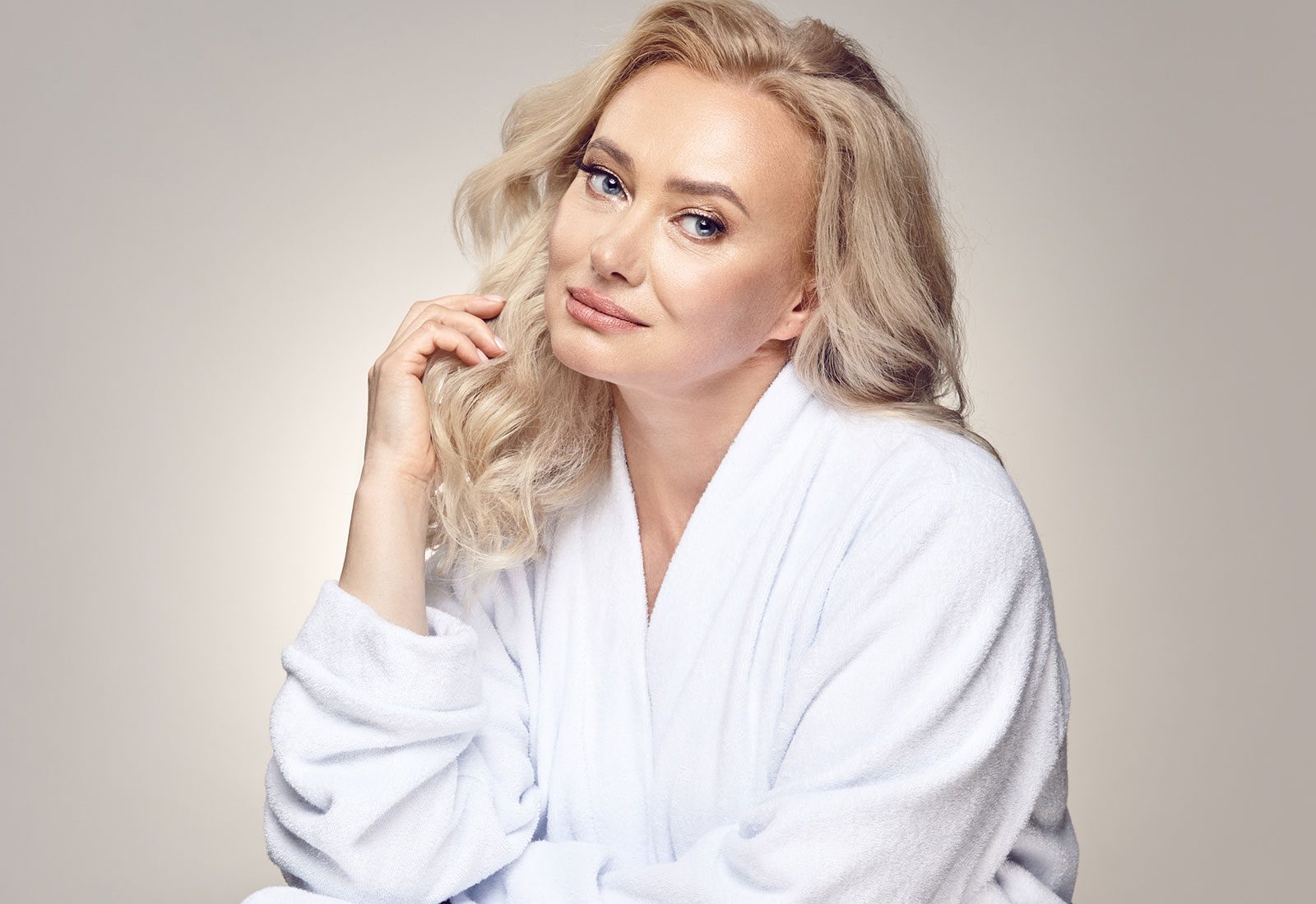 Blonde woman with defined cheekbones wearing a white robe