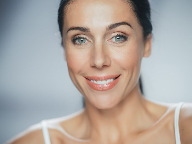 Close headshot of a smiling woman with defined cheekbones