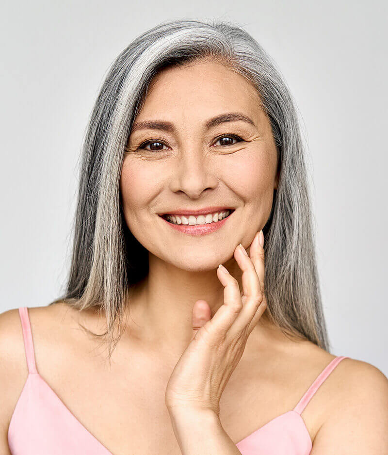 Middle aged woman smiling and caressing her jaw