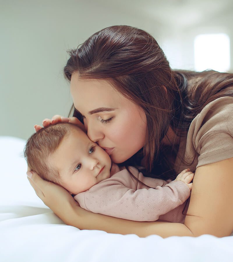 Mother kissing her newborn child's cheek
